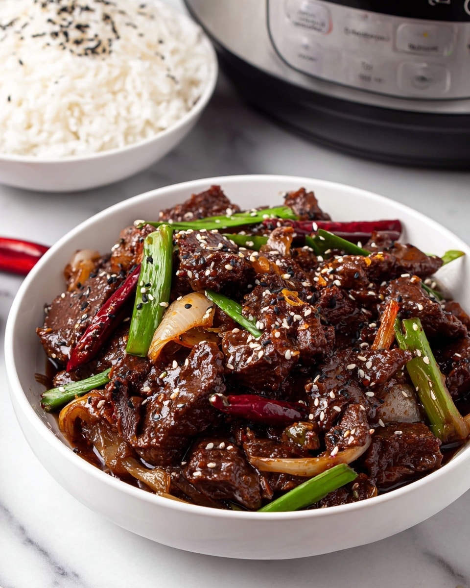 The image shows a white bowl filled with a dark brown stir-fried beef dish. The beef pieces are coated in a glossy sauce and mixed with sautéed onion slices, green onion stalks, and whole dried red chili peppers. White and black sesame seeds are sprinkled on top, adding a contrast of light and dark specks. Next to the bowl, there is a white bowl of white rice with some black sesame seeds on top. The dish is placed on a white marbled surface with a slow cooker visible in the background. photo taken with an iphone --ar 4:5 --v 7