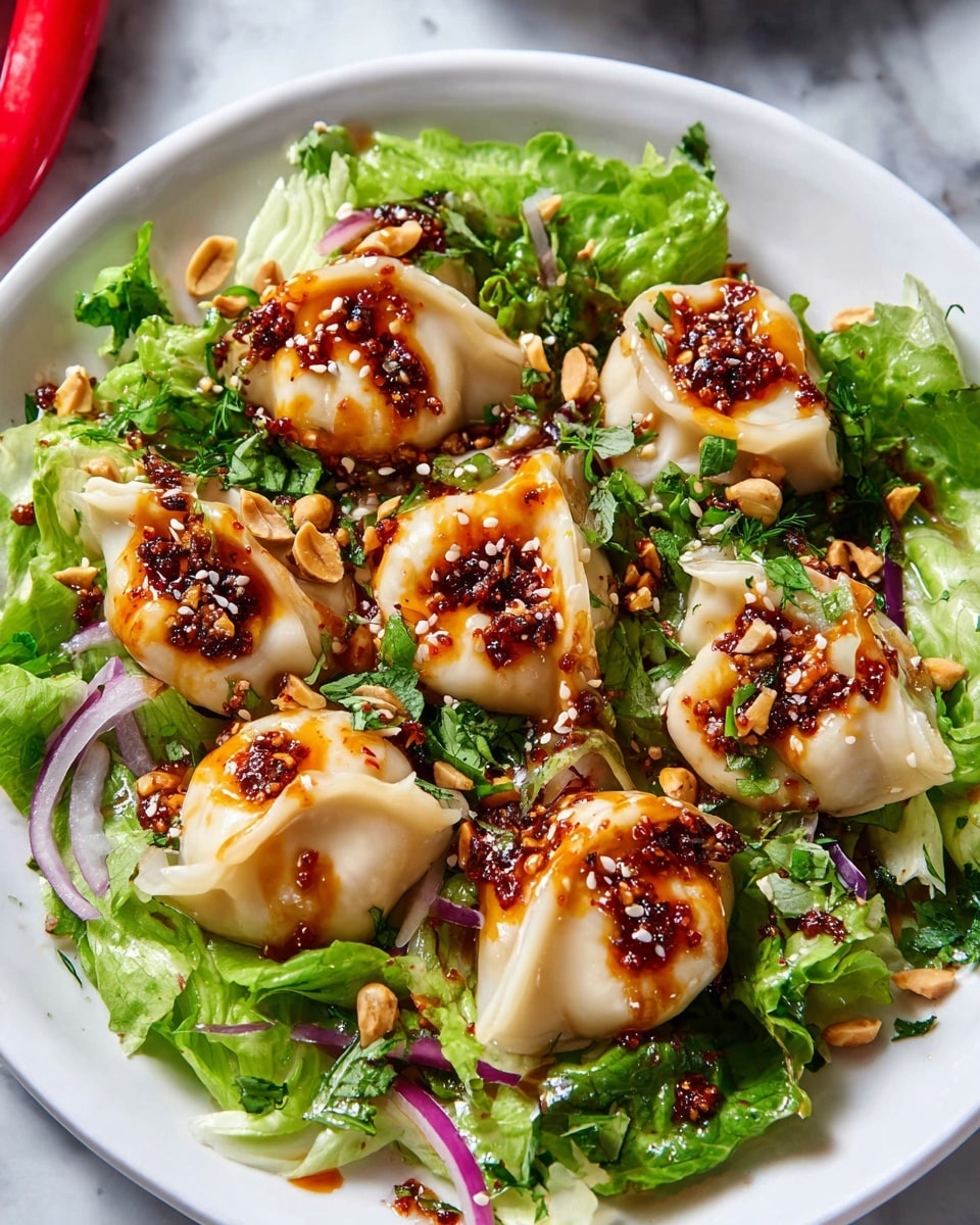 A wooden spoon holds one dumpling with a light tan, smooth, and slightly translucent dough wrapped around a filling, topped with a bright orange-red chili oil sauce that has visible chili flakes and minced nuts, sprinkled with white sesame seeds. The dumpling rests on two green leafy layers: a bright green frilly lettuce leaf on top and a darker veined red and green leaf underneath. More dumplings with the same chili oil and sesame seeds are blurred in the bright green leafy salad background. The whole scene is set on a white marbled surface. Photo taken with an iphone --ar 4:5 --v 7