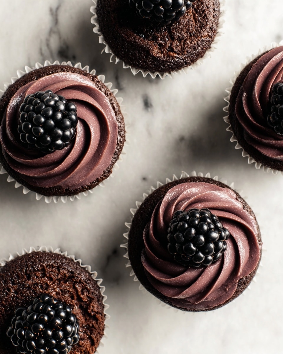 Five chocolate cupcakes are shown from above on a white marbled surface, three with a smooth dark purple swirl of frosting on top, each topped with a shiny black blackberry, and two without frosting, showing a rich, moist chocolate cake texture. Each cupcake is in a white paper liner. The frosting is thick with a velvety texture, paired with the glossy, bumpy surface of the blackberries. photo taken with an iphone --ar 4:5 --v 7
