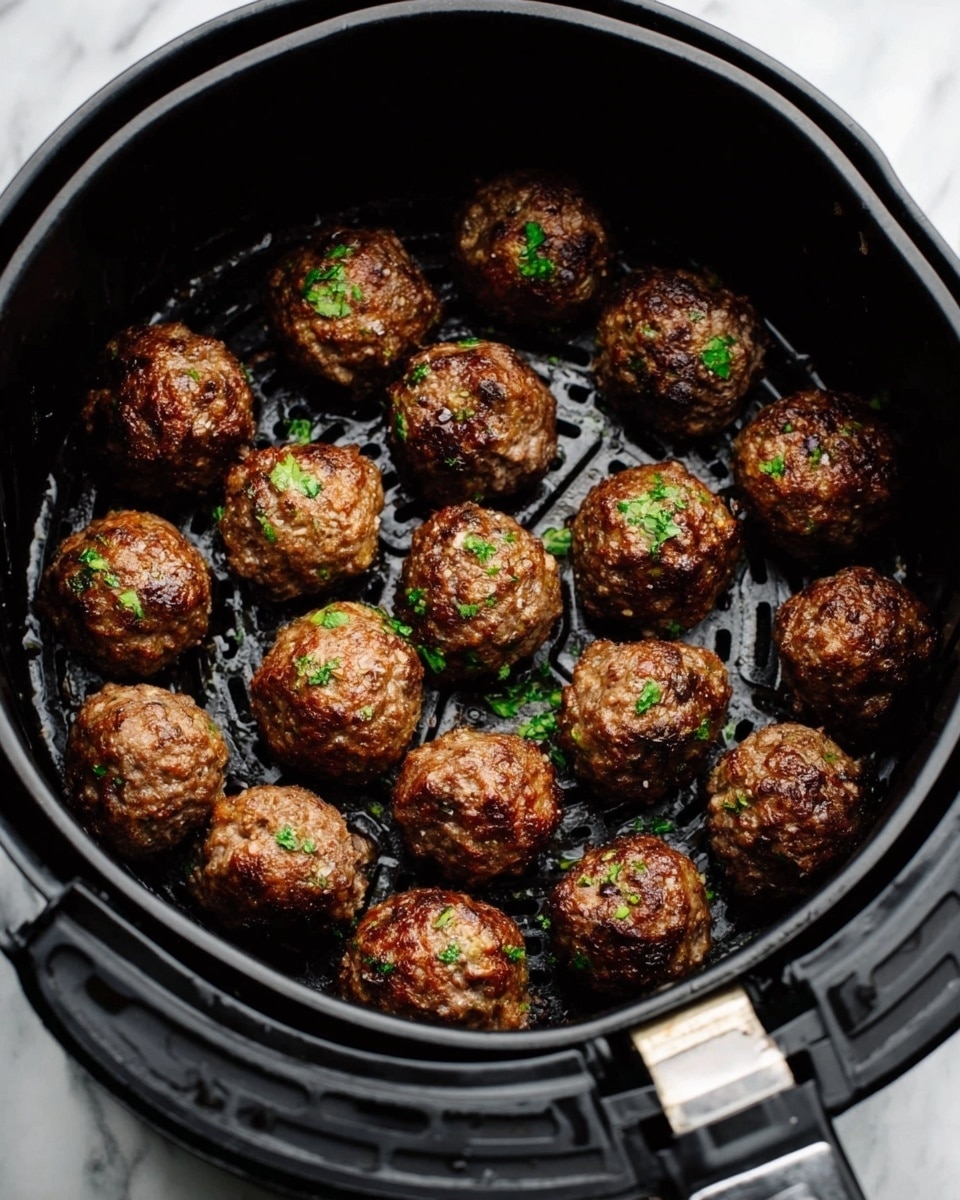 A white bowl holds a serving of spaghetti arranged in circular layers forming a nest, with six browned meatballs on top, each sprinkled with chopped green herbs. Fresh green basil leaves are placed beside the meatballs on the spaghetti. In the background, there is a small white bowl with red sauce partially visible. The scene is set on a white marbled surface with a red and white striped cloth beneath the bowl. photo taken with an iphone --ar 4:5 --v 7