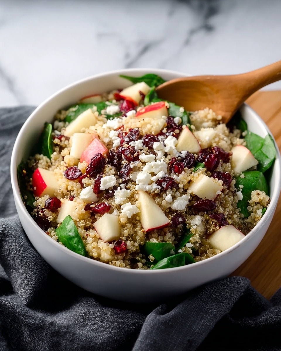 A white bowl with seven sections of fresh and colorful ingredients is held by two woman's hands with light pink nail polish against a white marbled texture. Starting from the top left and moving clockwise, there are dark dried cherries, light tan cooked quinoa, chunky brown walnuts, small chopped purple onion, bright green curly kale, white crumbly cheese, and diced red apple with white flesh and red skin. Each ingredient is neatly placed next to each other, creating a visually appealing mix of textures and colors. photo taken with an iphone --ar 4:5 --v 7