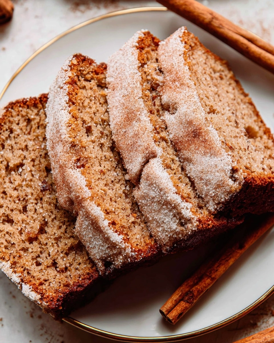 The image shows a loaf cake with a rough golden-brown crust topped with a layer of crumbly sugar and streusel, creating a textured, crunchy surface. The cake sits on a wooden cutting board that has visible grain and crumbs scattered around it. In the background, there are two red apples, a cinnamon stick, and small bowls of sugar or flour, all placed on a white marbled surface. The loaf is thick, with a visible crumb texture on the cut end, showing a moist yet firm interior. The lighting highlights the sugary topping and the warm tones of the cake. Photo taken with an iphone --ar 4:5 --v 7