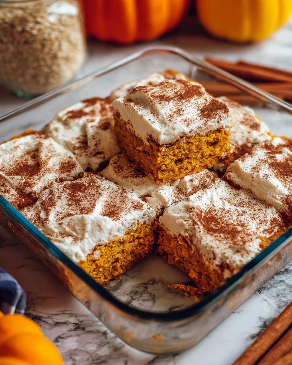 A glass baking dish holds six square pieces of a pumpkin dessert. Each piece has a thick orange base layer showing a soft, moist texture. On top of the base is a white creamy layer unevenly spread, with a dusting of brown cinnamon powder covering the entire surface. One piece is missing, revealing the orange base inside. The dish is set on a white marbled surface with a pumpkin, a jar of oats with cinnamon sticks, and a white plate with some food blurred in the background. Photo taken with an iphone --ar 4:5 --v 7