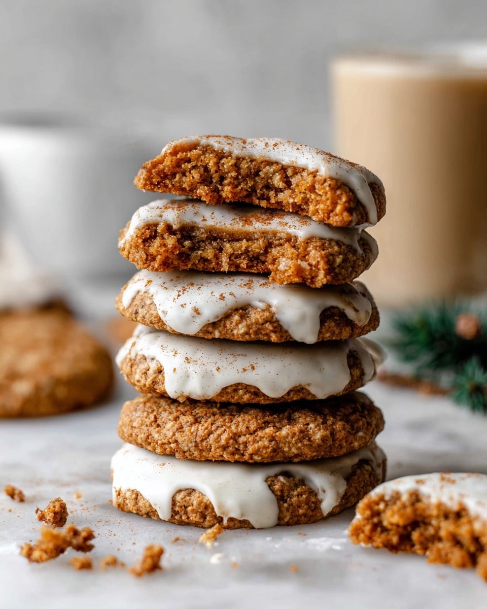 The image shows a collection of oatmeal cookies, some dipped halfway in a white icing that is lightly sprinkled with brown spice powder, giving a soft textured look to the icing. The cookies have a rough, slightly cracked golden-brown surface with visible oat flakes, and a few are partially eaten, showing their chewy inside. They are spread out on a white marbled surface, with small green pine sprigs placed around for decoration. A small white bowl filled with brown spice powder is also visible at the bottom right corner. photo taken with an iphone --ar 4:5 --v 7