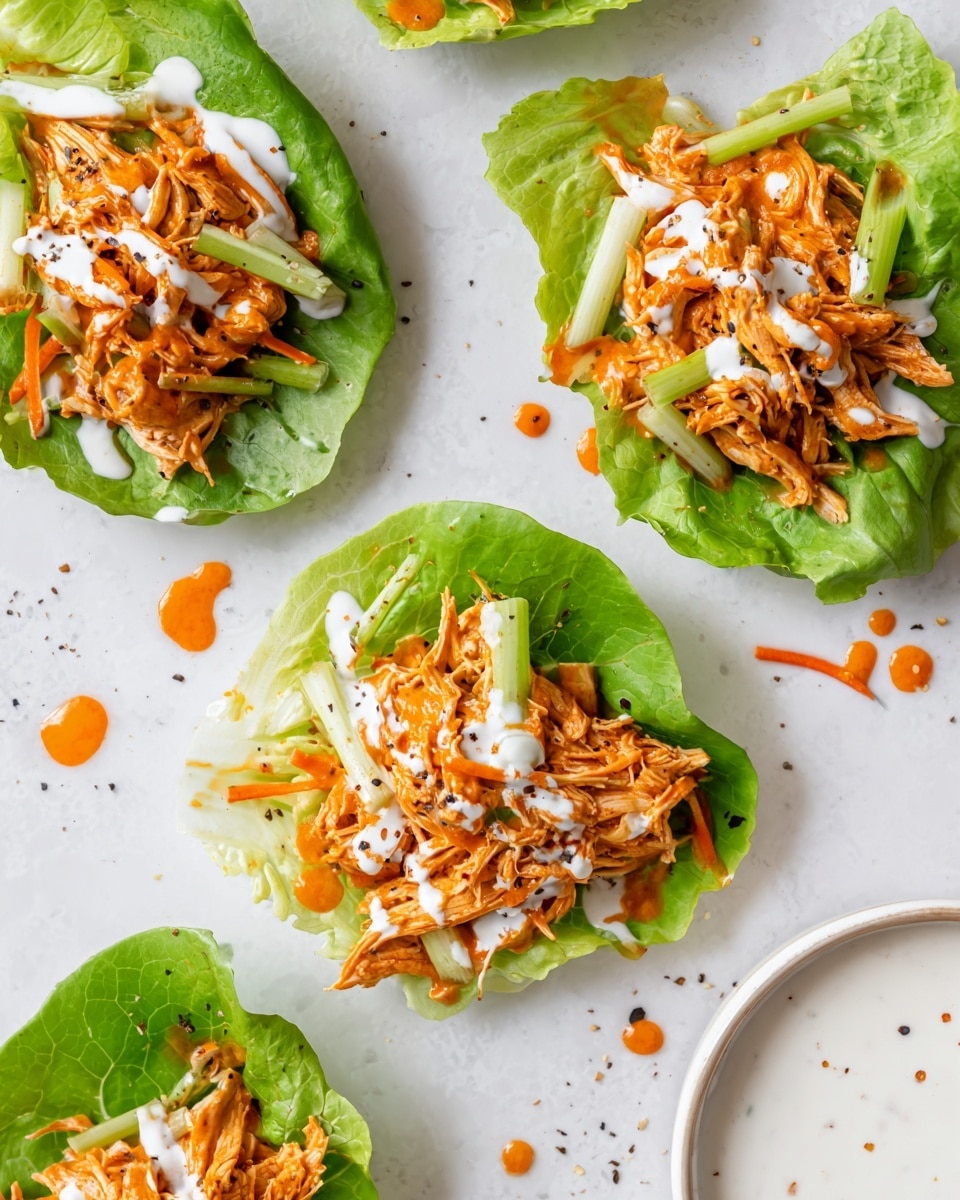 The image shows five lettuce cups arranged on a white plate with a white marbled texture background. Each cup has a bright green leafy lettuce base, holding a mix of shredded, orange and white chicken salad with small pieces of carrot and celery mixed in. The chicken mixture is topped with thinly sliced green onions and drizzles of creamy white dressing. The texture of the chicken salad looks moist and chunky with the veggies adding color contrast. Off to the side, there is a small white bowl filled with extra creamy dressing. photo taken with an iphone --ar 4:5 --v 7