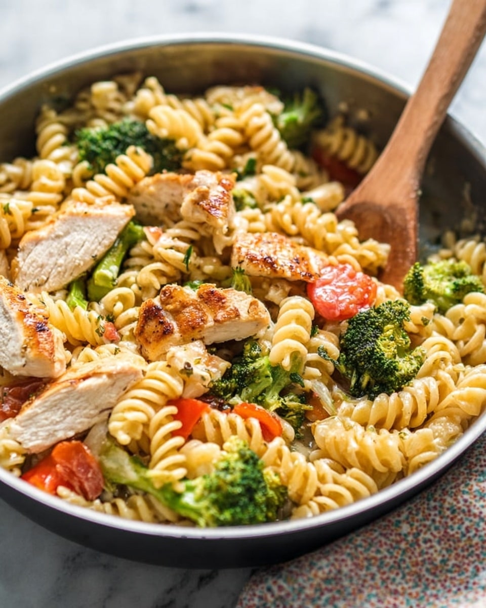 The image shows a close-up of a pan filled with cooked rotini pasta mixed with grilled chicken slices, bright green broccoli pieces, and chunks of red tomato. The pasta is pale yellow with a soft texture, while the grilled chicken slices have a golden brown outer layer with juicy white inside. The broccoli florets are vibrant and fresh, adding a pop of green, and the tomato pieces add a splash of red throughout the dish. A wooden spoon is partially visible on the right side, stirring the mixture. The scene is set on a white marbled surface with a soft patterned cloth in the background. photo taken with an iphone --ar 4:5 --v 7
