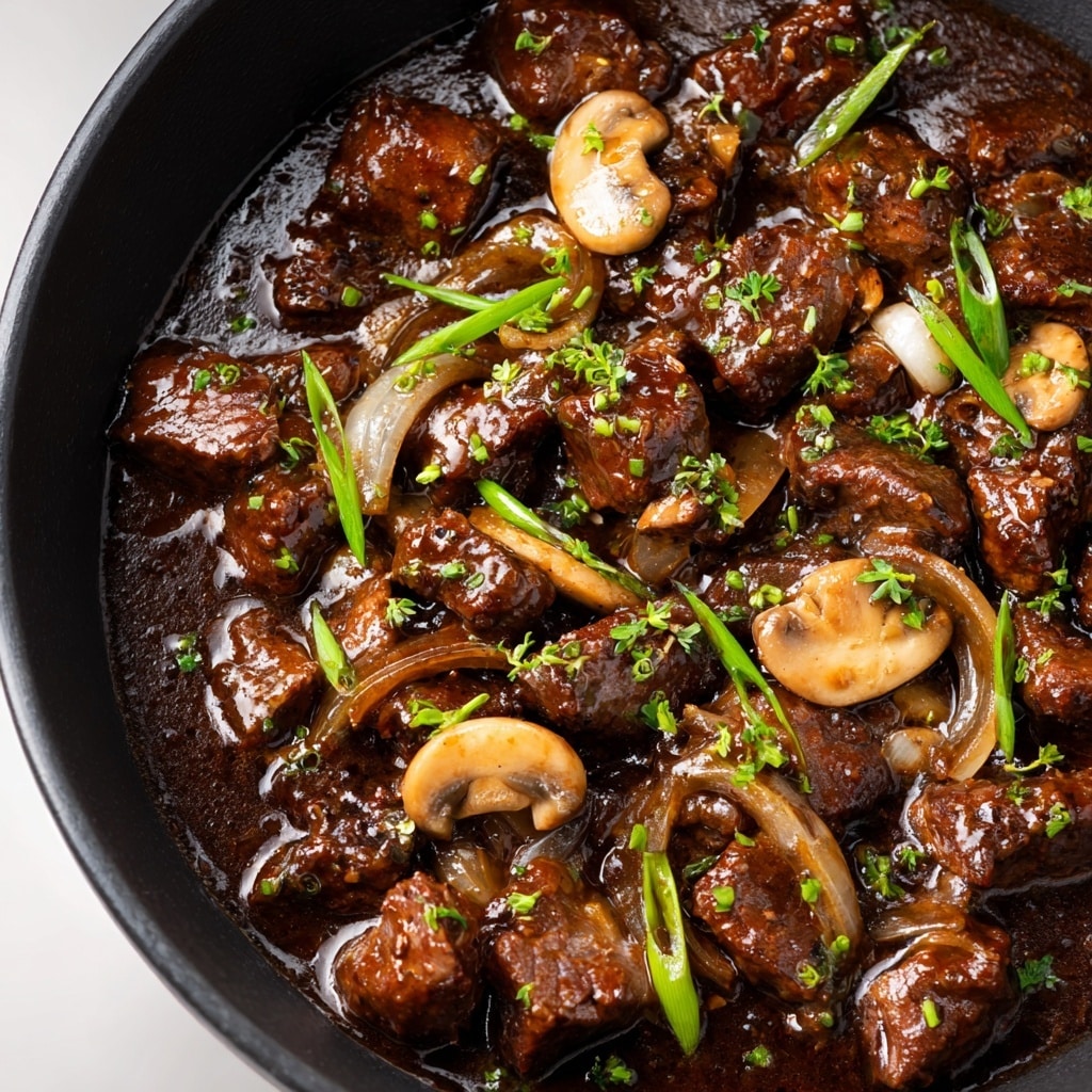 The image shows a white plate with two main parts of food: on one side, there are dark brown pieces of beef covered in a glossy, rich brown mushroom sauce, scattered with light brown sliced mushrooms and sprinkled with small green herb pieces; on the other side, there is a mound of creamy white mashed potatoes with a fluffy texture, also topped with a few green herbs. The plate sits on a white marbled surface with a blue and white striped cloth partially visible at the edge. Photo taken with an iphone --ar 4:5 --v 7