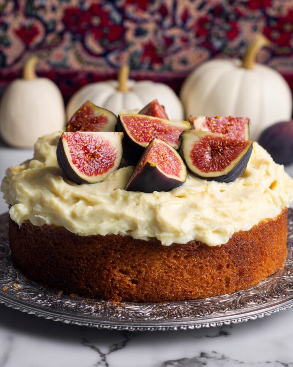 A slice of cake is placed on a fancy silver plate in the front. The cake has two layers: a thick base layer of light yellow sponge with visible dark fruit pieces mixed throughout, and a top layer of creamy white frosting that is thickly spread. On top of the frosting, there are two halves of fresh fig with a deep red center and dark purple skin. In the background, there is a full cake on an ornate silver tray with the same creamy frosting and fig pieces on top. The whole scene is set on a white marbled surface with small decorative pumpkins and a candle holder nearby. photo taken with an iphone --ar 4:5 --v 7