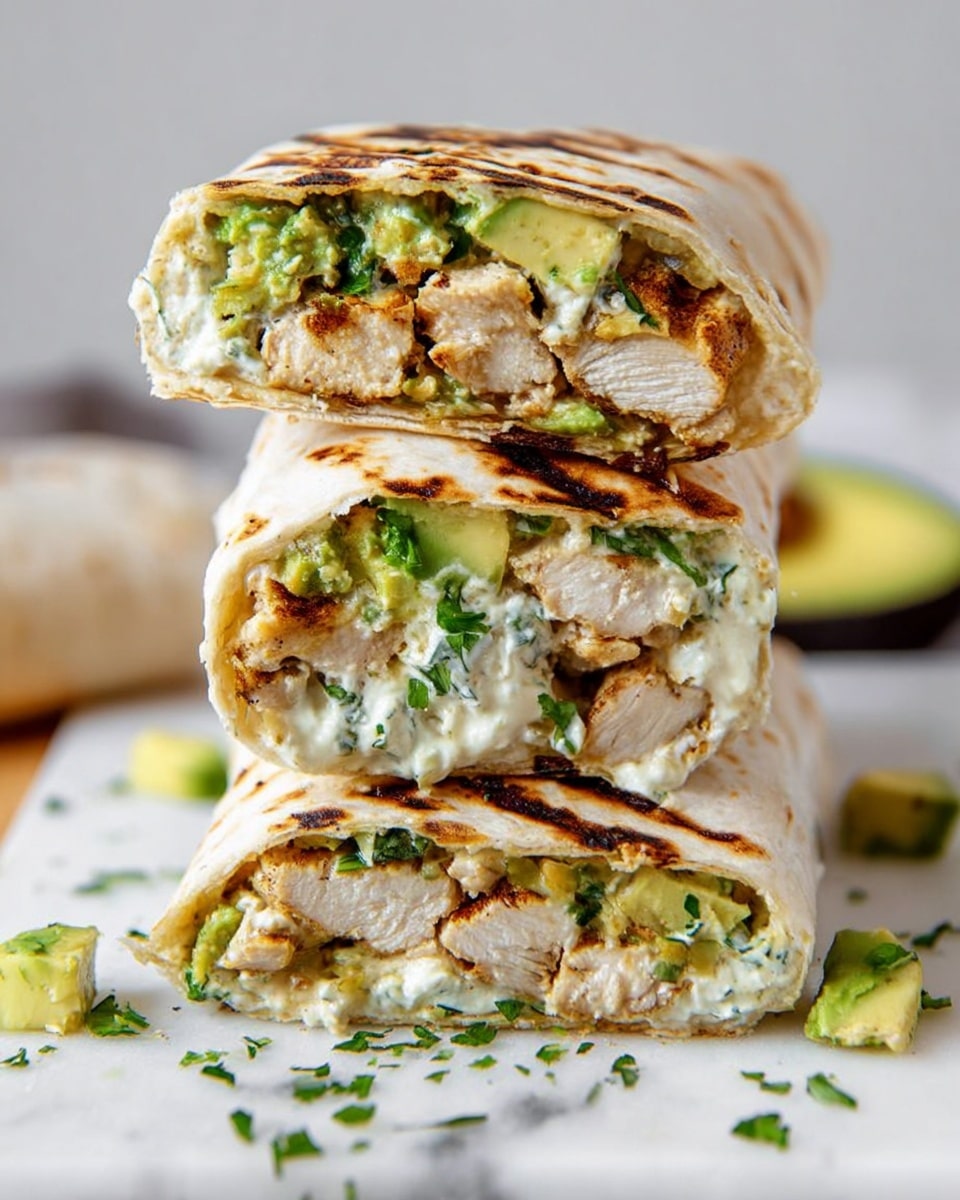 The image shows a stack of three grilled chicken wraps placed on a piece of flatbread on a white marbled surface. Each wrap is sliced in half and stacked on top of each other, revealing layers inside: the first layer is a light brown grilled chicken with visible texture, followed by a creamy white cheese or sauce, bright green chunks of avocado, and bits of fresh herbs mixed in. The tortillas are white with dark grilled marks. There are small pieces of avocado and chopped herbs scattered around the base, adding to the fresh and appetizing look. The overall composition is close-up, bright, and sharp, with a clean light background. Photo taken with an iphone --ar 4:5 --v 7