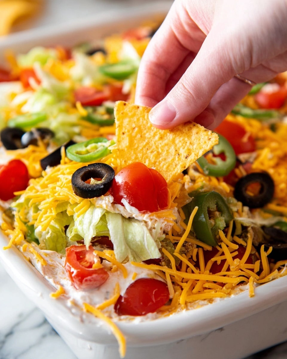 A white pie dish filled with layered salad sits on a wooden round board over a white marbled surface. The salad has a base of green lettuce leaves, topped with a mix of sliced black olives, chopped red tomatoes, and sliced green jalapeños. The top layer is sprinkled evenly with shredded yellow cheddar cheese. Around the main dish, there are clear bowls of tortilla chips, chopped tomatoes, shredded cheese, and black olive slices. The scene is bright and fresh with a clean, white marbled background. photo taken with an iphone --ar 4:5 --v 7