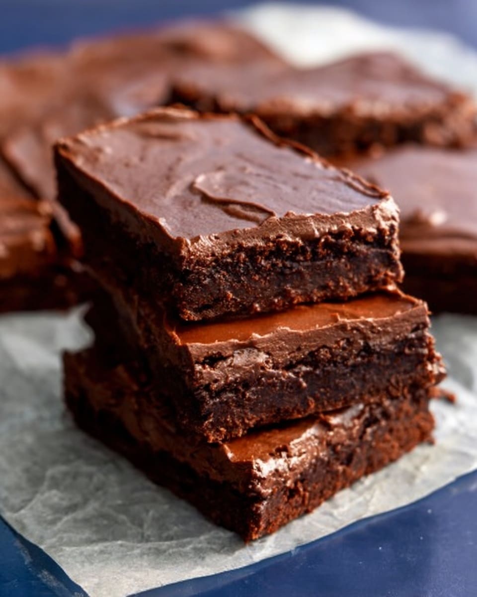 The image shows several rectangular chocolate brownies arranged closely on a white marbled surface. Each brownie has one thick layer of smooth, creamy chocolate frosting spread evenly on top, with small textured swirls and strokes visible. The brownies display a rich, dark brown color beneath the frosting, which looks moist and dense. The photo is clear and focused on the front center brownie, with others partially visible around it. photo taken with an iphone --ar 4:5 --v 7