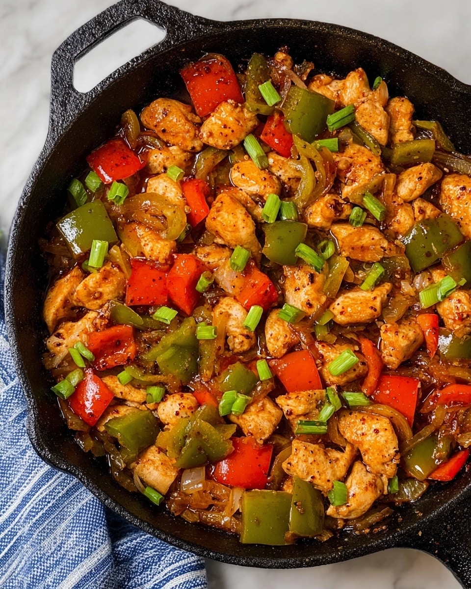 The image shows a close-up of a cooked dish in a black cast iron skillet, featuring three main layers: the first layer consists of browned, tender chicken pieces with a golden crust, scattered throughout the skillet. The second layer has chunks of green and red bell peppers with a shiny, slightly soft texture, mixed evenly among the chicken. The third layer shows small bits of cooked onions and sliced green onions sprinkled on top, adding a fresh green pop against the warm colors. The dish is coated lightly with a glossy, slightly oily sauce, with visible black pepper seasoning giving a speckled texture. The skillet sits on a white marbled surface with a blue and white striped cloth partially visible at the side. Photo taken with an iphone --ar 4:5 --v 7