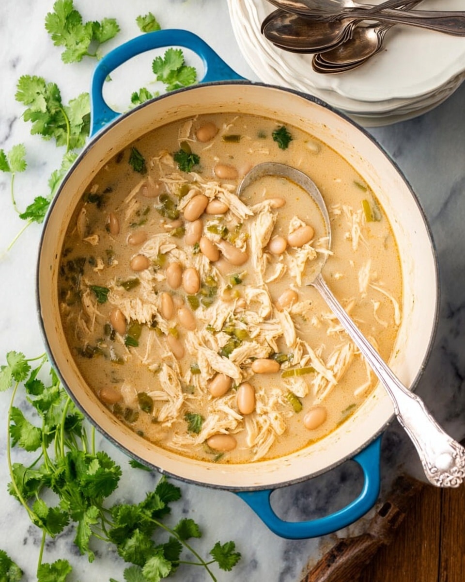 A white bowl filled with a creamy white chicken chili that shows white beans and shredded chicken soaked in a light beige broth as the base layer. On the top right side of the bowl, there is a heap of shredded yellow and white cheese with a soft texture, next to a cluster of three bright green jalapeño slices placed on top of the chili. Above the chili, towards the left, there is a small pile of thin, crunchy tortilla strips in white, dark purple, and red colors. On the bottom right, a sprinkle of fresh green cilantro leaves adds color contrast. A silver spoon stands inside the bowl on the left side. The bowl is set on a white marbled surface, with additional shredded cheese and bowls of jalapeños and colored tortilla strips blurred in the background. Photo taken with an iphone --ar 4:5 --v 7