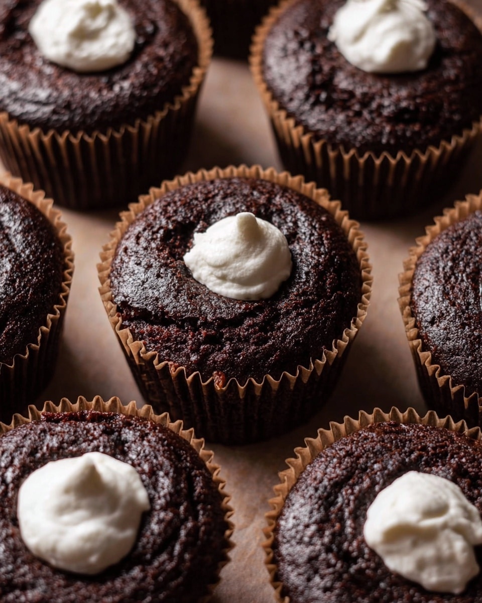 The image shows several rich chocolate cupcakes with three distinct layers: the bottom layer is dark, moist chocolate cake, the middle is a thick, white marshmallow filling that looks soft and creamy, and the top layer is a chocolate mousse that is lighter brown and smooth. Each cupcake is topped with a large toasted marshmallow that is golden with charred spots, creating a slightly crispy outer texture. The cupcakes are placed in white cupcake liners, and the background surface is a warm, dark wooden texture with some cocoa powder scattered around. Photo taken with an iphone --ar 4:5 --v 7